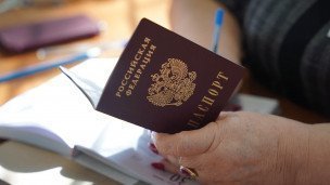 Сотрудница оформляет документы и держит паспорт в руках