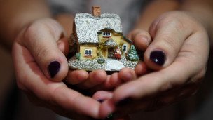 Женщина с ребенком держат макет дома