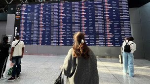 Люди у электронного табло с информацией о вылетах в аэропорту