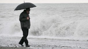 Мужчина под зонтом на берегу Черного моря в Сочи