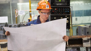 Рабочий на заводе с чертежом