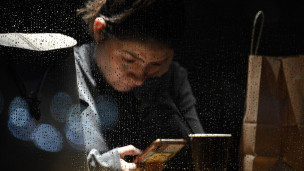 Девушка сидит в кафе во время дождя в телефоне 