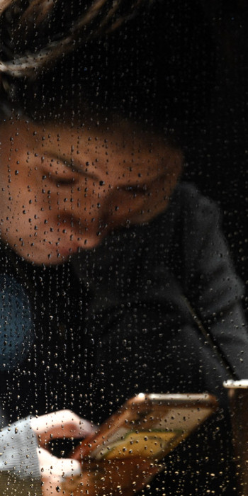 Девушка сидит в кафе во время дождя в телефоне 