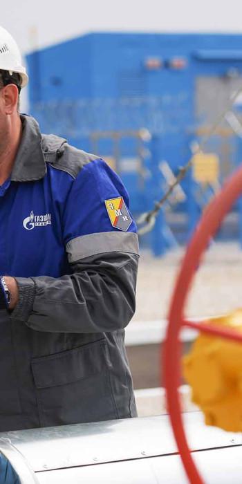 сотрудник газовой службы поворачивает вентель газовой трубы