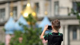 Ребенок в парке фотографирует на смартфон