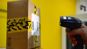 Сотрудник сканирует штрих-код с коробки в пункте выдачи заказов 
