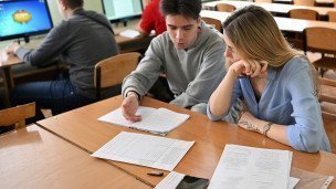 Студенты на практических занятиях Студент объясняет однокурснице тему на заднем плане сидят другие студенты за компьютерами