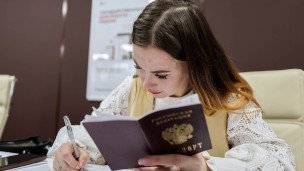 Сотрудница в МФЦ с паспортом заполняет документы