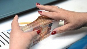 Сотрудница банка пересчитывает купюры номиналом в пять тысяч рублей 