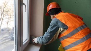 Рабочий проводит отделочные работы в подъезде жилого дома