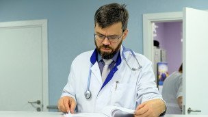 Врач читает историю болезни пациента 