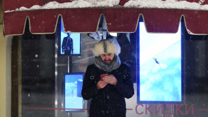 Мужчина с телефоном зимой на улице в меховой шапке