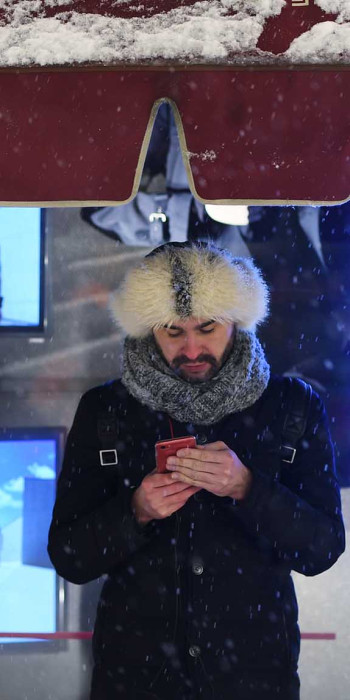 Мужчина с телефоном зимой на улице в меховой шапке