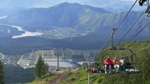 Отдыхающие в кресле подъемника на территории всесезонного курорта Манжерок