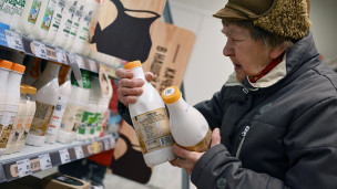 Пожилая женщина выбирает маркированные молочные продукты в магазине