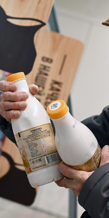 Пожилая женщина выбирает маркированные молочные продукты в магазине