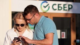 Мужчина и женщина с телефоном около банка Сбер