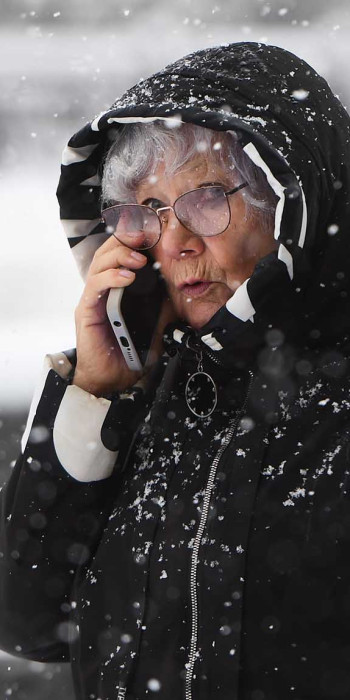 Женщина во время снегопада разговаривает по телефону