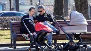 Женщина и мужчина с колясками в парке на скамейке