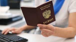 Госслужащий держит в руках паспорт РФ 