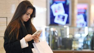 Pokupatelnica-v-magazine-smotrit-v-telefon