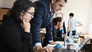 Старшеклассник перед ноутбуком рядом учитель 