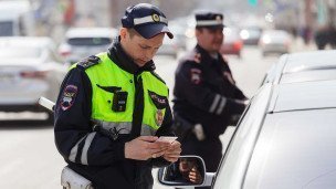 Сотрудник дорожно-патрульной службы проверяет у автомобилиста водительское удостоверение