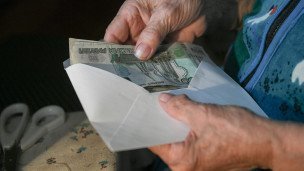 Пожилая женщина достает деньги из конверта