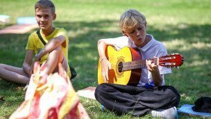 Мальчик в лагере играет на гитаре 