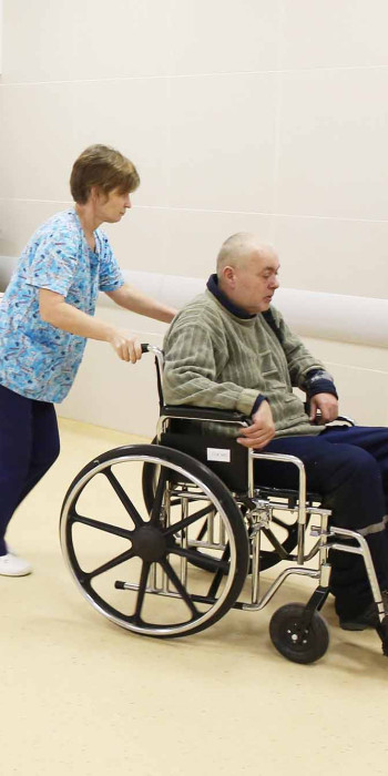 женщина катит мужчину на инвалидной коляске