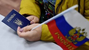 Крупный план в руках женщины паспорт гражданки Украины и российский флажок 