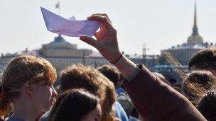 Бумажный кораблик в руках на фоне реки