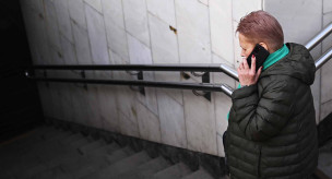 женщина с телефоном заходит в подземный переход