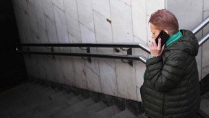 женщина с телефоном заходит в подземный переход