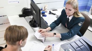 Сотрудница берет документы у посетителя 