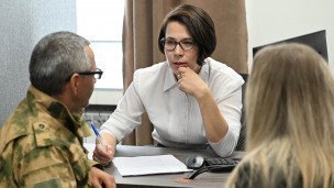 Сотрудница помогает военному оформлять документы на льготы