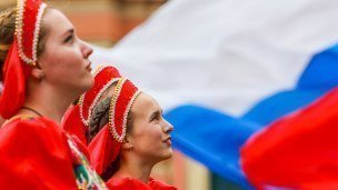 Девушки в национальных костюмах на фоне российского флага