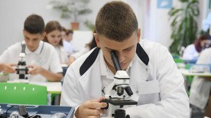 Ученик с микроскопом на уроке