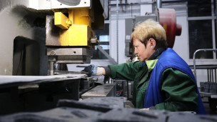 Сотрудница завода работает за станком