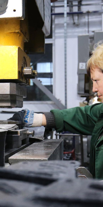 Сотрудница завода работает за станком