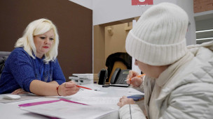 Жительница Мариуполя заполняет документы в отделении многофункционального центра