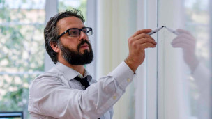 молодой ученый пишет на доске маркером