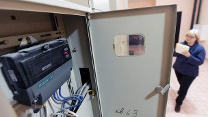 Женщина с квитанцией около счетчиков в подъезде