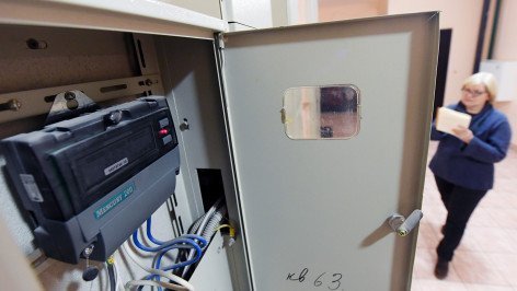 Женщина с квитанцией около счетчиков в подъезде