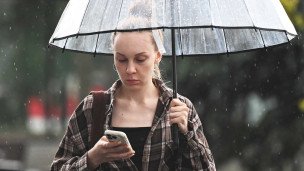 Девушка с телефоном под зонтом на улице