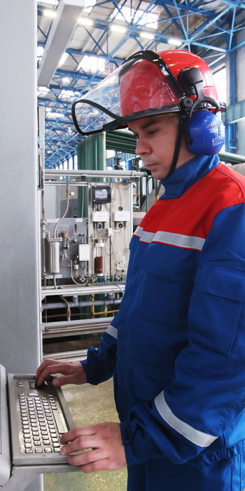 Работник у контрольного стенда за работой щеточного аппарата генератора в машинном зале