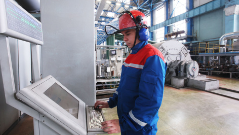 Работник у контрольного стенда за работой щеточного аппарата генератора в машинном зале