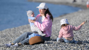 женщина отдыхает на берегу моря с двумя детьми