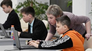 Школьники перед ноутбуками, на переднем плане преподавательница 