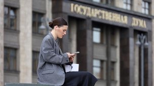 Девушка с телефоном на фоне здания Государственной думы